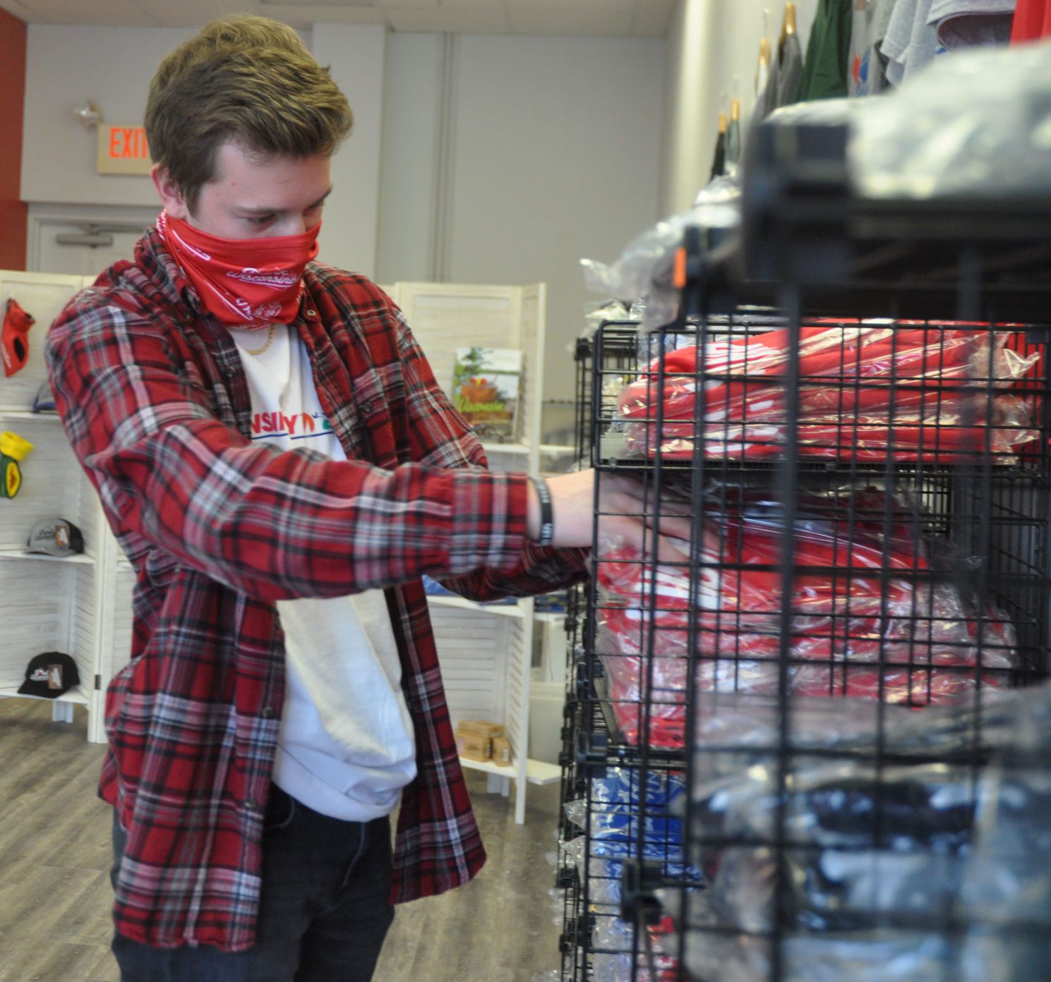 Dillon Murphy, Drink Wisconsinbly store employee, arranges some T-shirts that are offered at the store